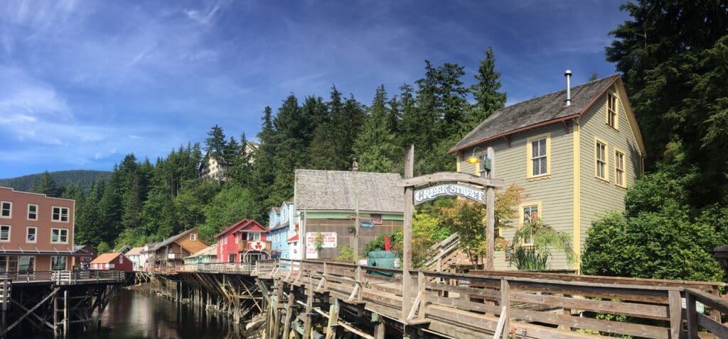 Creek Street Colorful historic buildings on a boardwalk above water behind a "Creek Street" sign